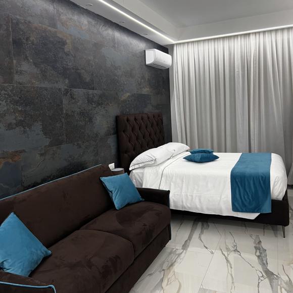 Elegant modern room with bed and sofa, blue and brown tones, cozy atmosphere.