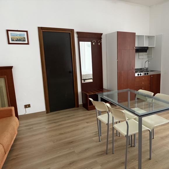 Spacious modern studio, bright and cozy, featuring a kitchen and glass table.