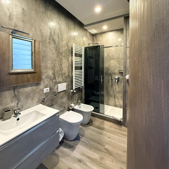 Elegant modern bathroom with gray walls, wooden floor, and glass shower.