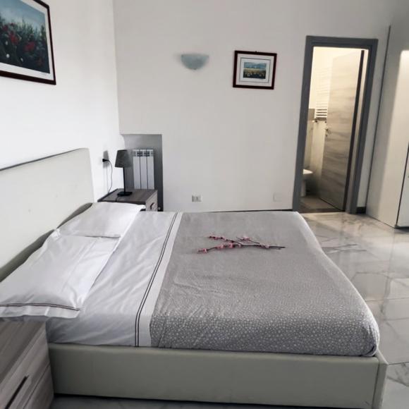 Bright room with elegant bed and modern bathroom, evoking serenity.