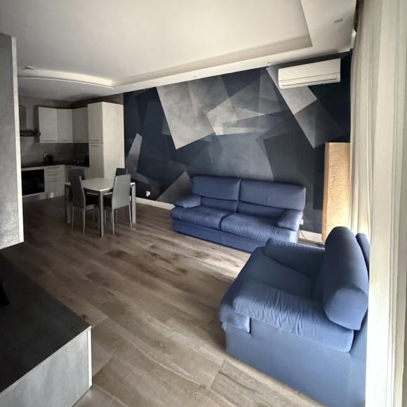 Modern living room with blue sofas, geometric wall, and soft lighting.