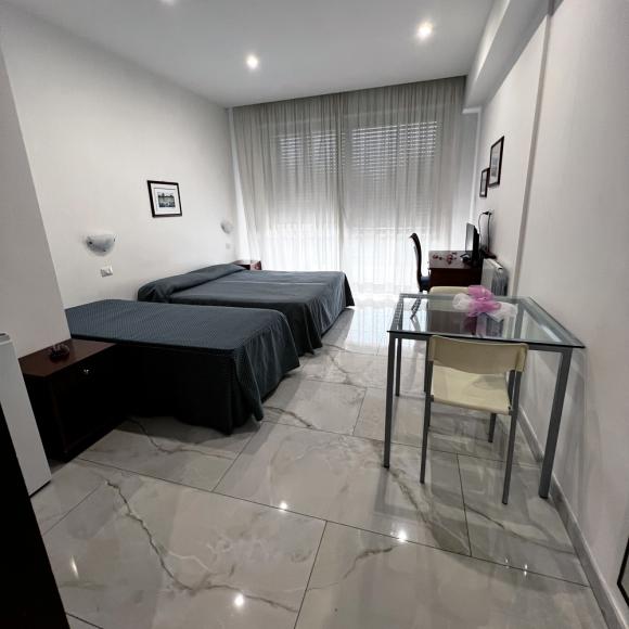 Bright room with twin beds, modern desk, and glossy marble floor.