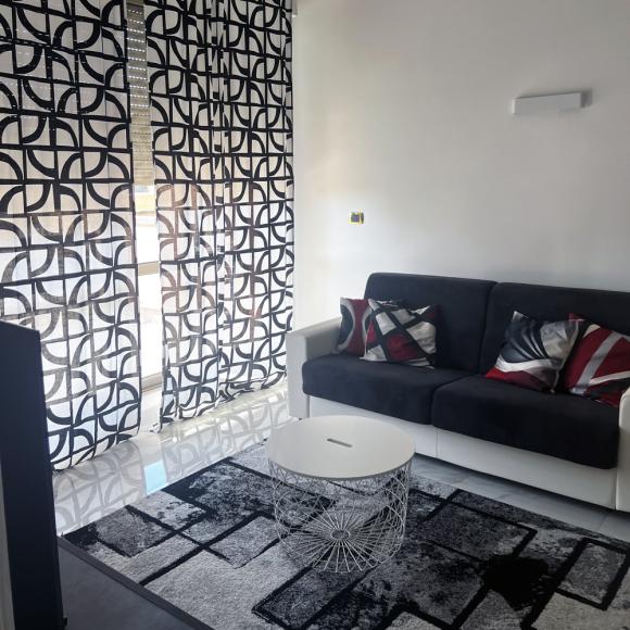 Modern living room, geometric curtains, cozy sofa, colorful pillows, elegant coffee table.