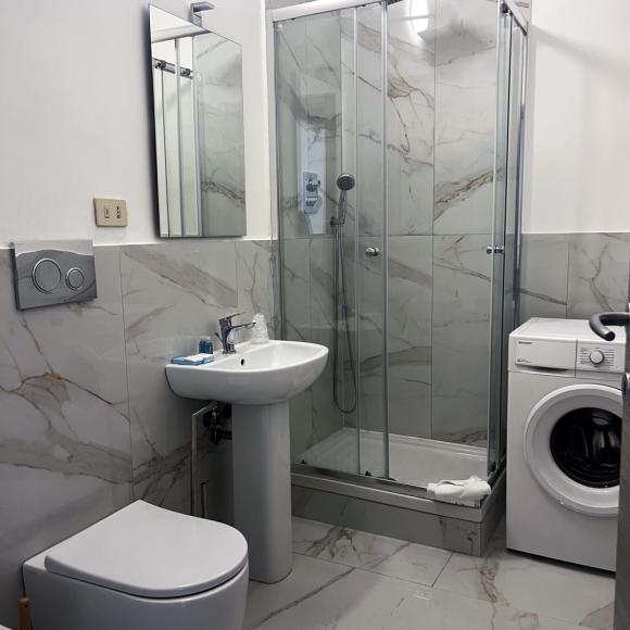 Modern, bright, and tidy bathroom with shower, washing machine, and elegant fixtures.
