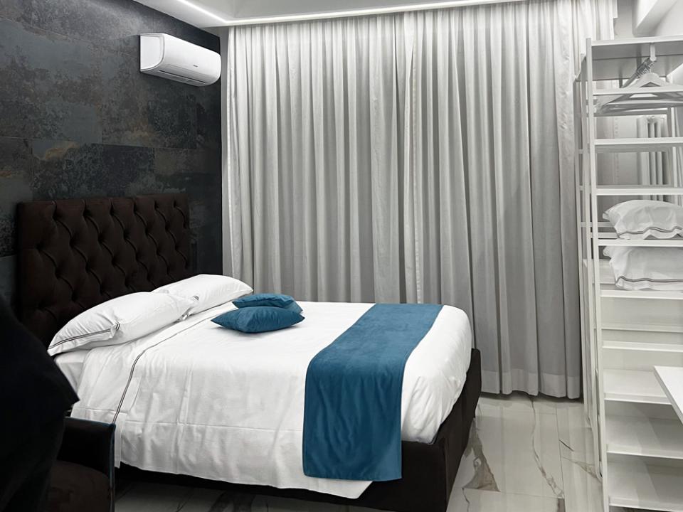 Modern, elegant room with white bed and blue accents, cozy and relaxing atmosphere.